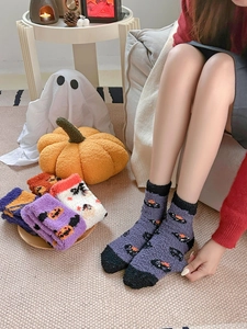 Cozy Halloween fuzzy crew socks with black cat and pumpkin motifs in festive setting