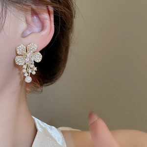 Macro view of gold flower earrings with zircon petals and hanging white pearls