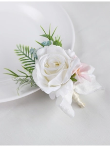 Detailed close-up of white silk rose boutonniere with green leaves and ribbon for wedding