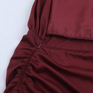 Detail of burgundy satin dress showing side zipper, ruched fabric, and waist cutout detail