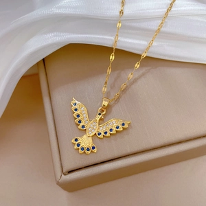 Golden phoenix pendant necklace with blue and clear crystals on a white silk background