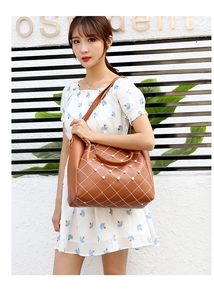 Sac fourre-tout marron avec surpiqûres blanches et perles porté par un modèle