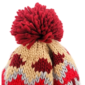 Detailed macro view of a soft knit beanie featuring a large fluffy dark red yarn pom-pom top