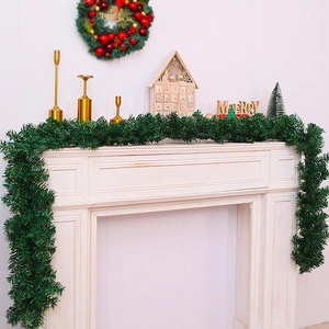 Detail of green artificial Christmas garland draped over a fireplace for holiday decor