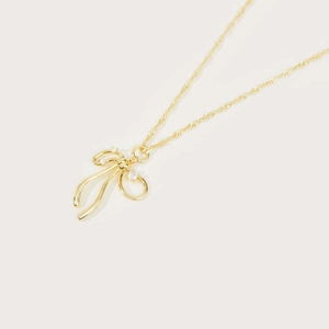 Close-up of gold-plated bow necklace with sparkling zircon stones on minimalist background