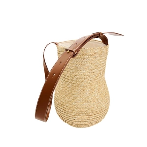 Gourd-shaped straw woven shoulder bag with brown leather strap on a white background