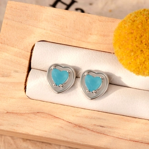 Elegant heart-shaped blue zircon stud earrings set in polished silver steel on a display case