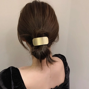 Close-up of matte gold metal hair ring on model's ponytail for a minimalist chic look