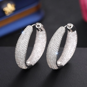 Close-up of pavé set white zircon hoop earrings on black leather display base