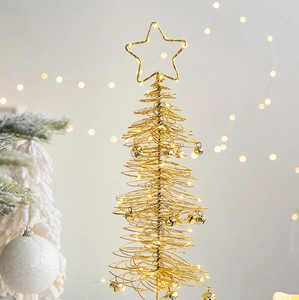 Close-up of golden iron Christmas tree with warm LED lights and small bells ornament
