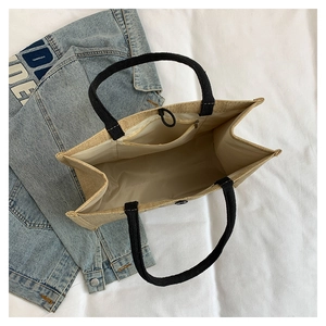 Interior detail of linen tote bag showing zipper pocket, magnetic buckle, and black handles