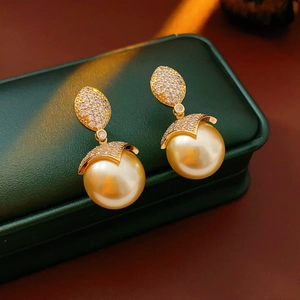 Dettaglio di orecchini placcati oro 18k con grandi perle dorate e piccoli cristalli