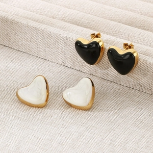 Detailed macro view of black and white heart enamel earrings with gold plating