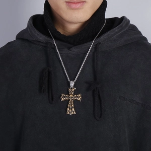 Detailed close-up of a gold skull cross pendant paired with a silver rope chain on a model