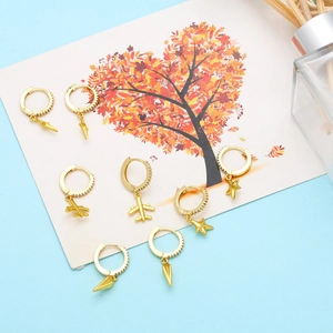 Detailed view of gold hoop earrings with cross, star, and airplane charms on a card