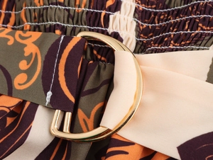 Macro detail of elastic pleated waist with golden buckle and retro floral print
