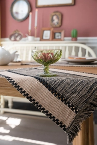 Close-up of woven table runner with contrast stitching, fringe detail, and textured fabric