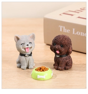 Close-up of resin miniature puppy figurines with pet food bowl on a wooden desk surface