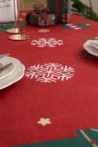 Close-up of red Christmas tablecloth featuring white snowflakes and green tree patterns