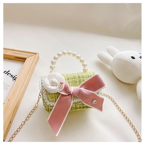 Detail of tweed girls crossbody bag with lace trim, pink bow and pearl handle