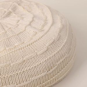Close-up of beige knit beret showing detailed crochet texture and wave pattern