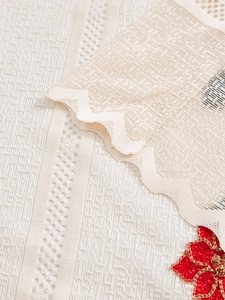 Detail of beige sheer curtain with geometric mesh, wavy lace edge and red flower embroidery