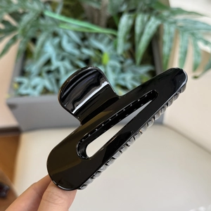 Primo piano di un grande fermaglio per capelli nero lucido con design a goccia traforata