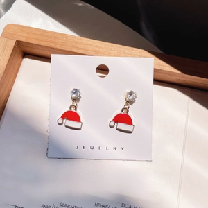 Close-up of red and white Santa hat earrings with clear zircon stones on a jewelry card