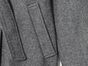 Detailed macro view of dark grey wool blend fabric and premium pocket flap stitching
