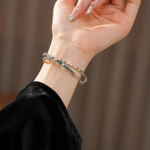 Close-up of stacked silver bangles featuring colorful rectangular zircon pavé and link chain