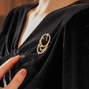 Détail d'une broche ovale plaquée or 18 carats avec glands en zircon sur velours noir