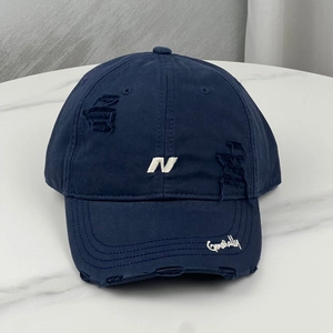 Detailed close-up of a navy baseball cap featuring white N embroidery and distressed holes