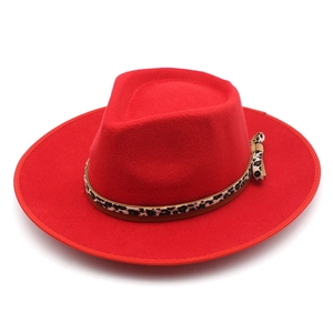 Detail of red wool fedora hat featuring a leopard print band and small side bow detail