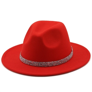 Détail d'un chapeau fedora rouge vif avec un bandeau décoratif en paillettes argentées