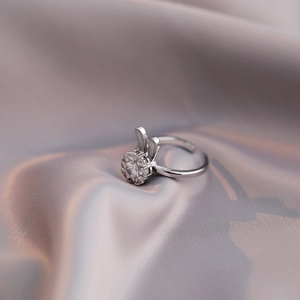 Adjustable silver bunny ring with sparkling zircon stones on a gray silk background