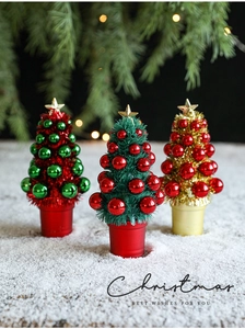 Three mini colorful Christmas trees with golden stars on snowy background