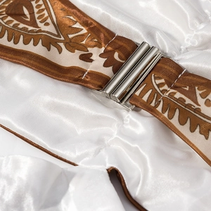Dettaglio fibbie in metallo argento su tessuto bianco e cinturini con paisley