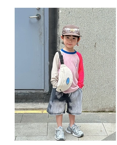 Street style shot of child wearing canvas crossbody bag and color-block t-shirt outfit
