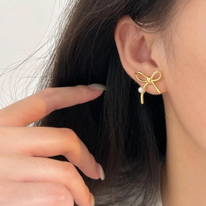 Elegant 925 silver bow stud earrings with white pearls shown on a female model