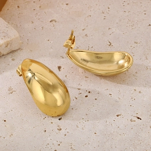 Golden teardrop stud earrings in polished stainless steel on a minimalist stone background
