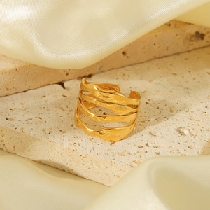 Detailed view of gold irregular layered ring on travertine stone with silk background