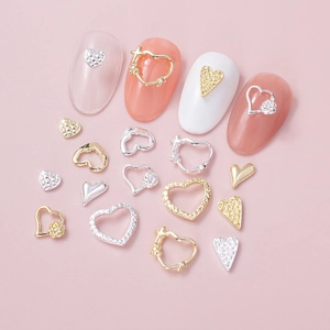 Detailed close-up of heart-shaped alloy nail charms in gold and silver with rhinestones