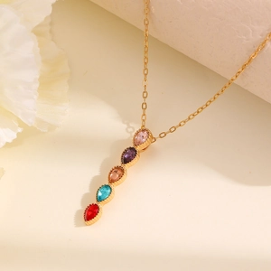 Macro detail of gold necklace with vertical colorful teardrop-shaped gemstone pendants