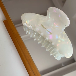 Detail of white pearlescent resin hair claw clip with golden France Handmade text
