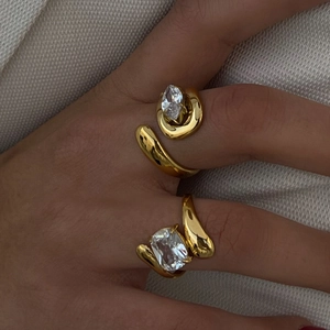 Detail of two gold irregular open rings with large oval and radiant cut zircons