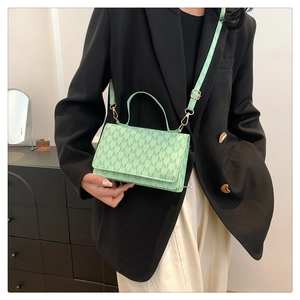 Mint green crossbody bag with M-letter print and gold hardware shown on a model