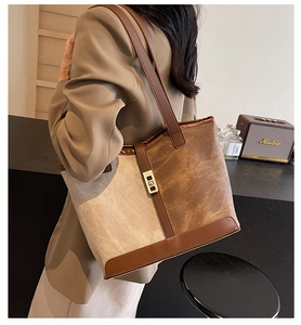 Detailed shot of a brown leather and beige canvas tote bag with gold hardware on a model