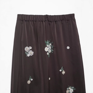 Jupe midi élégante en satin marron foncé avec broderie florale pailletée sur fond blanc