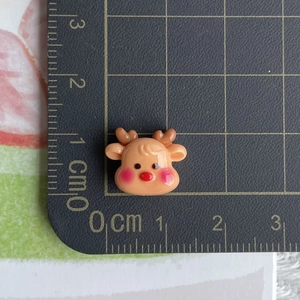 Macro view of a mini resin reindeer charm with dimensions shown on a ruler guide