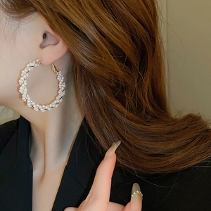 Grandes créoles dorées torsadées avec perles blanches portées par un mannequin femme
